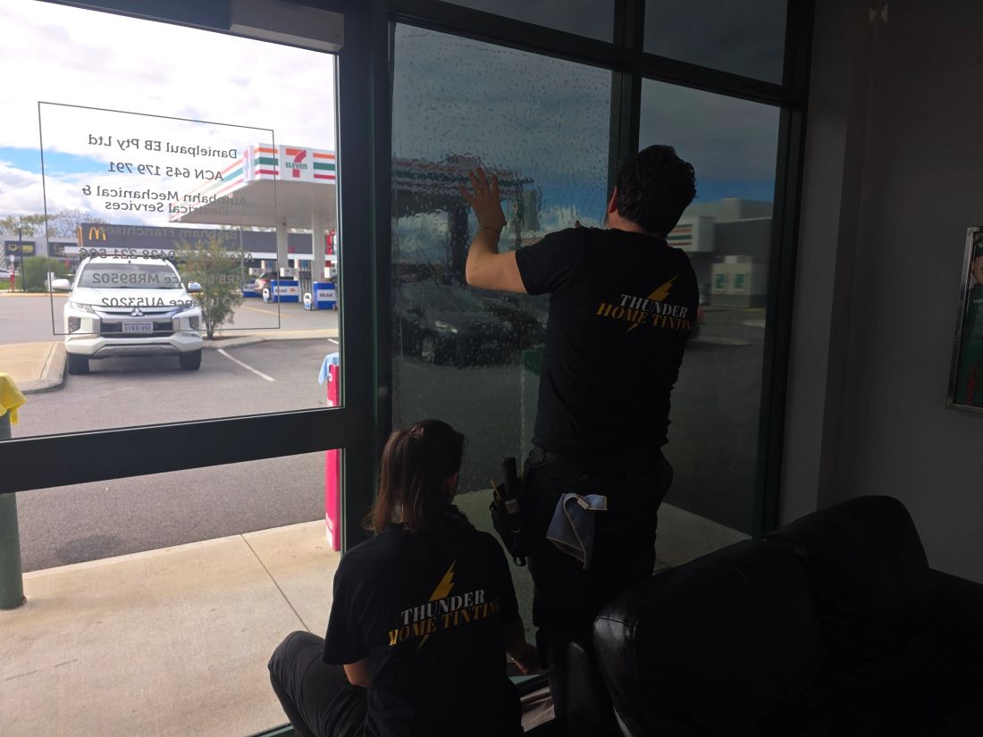 Thunder technicians fitting window film to commercial glass